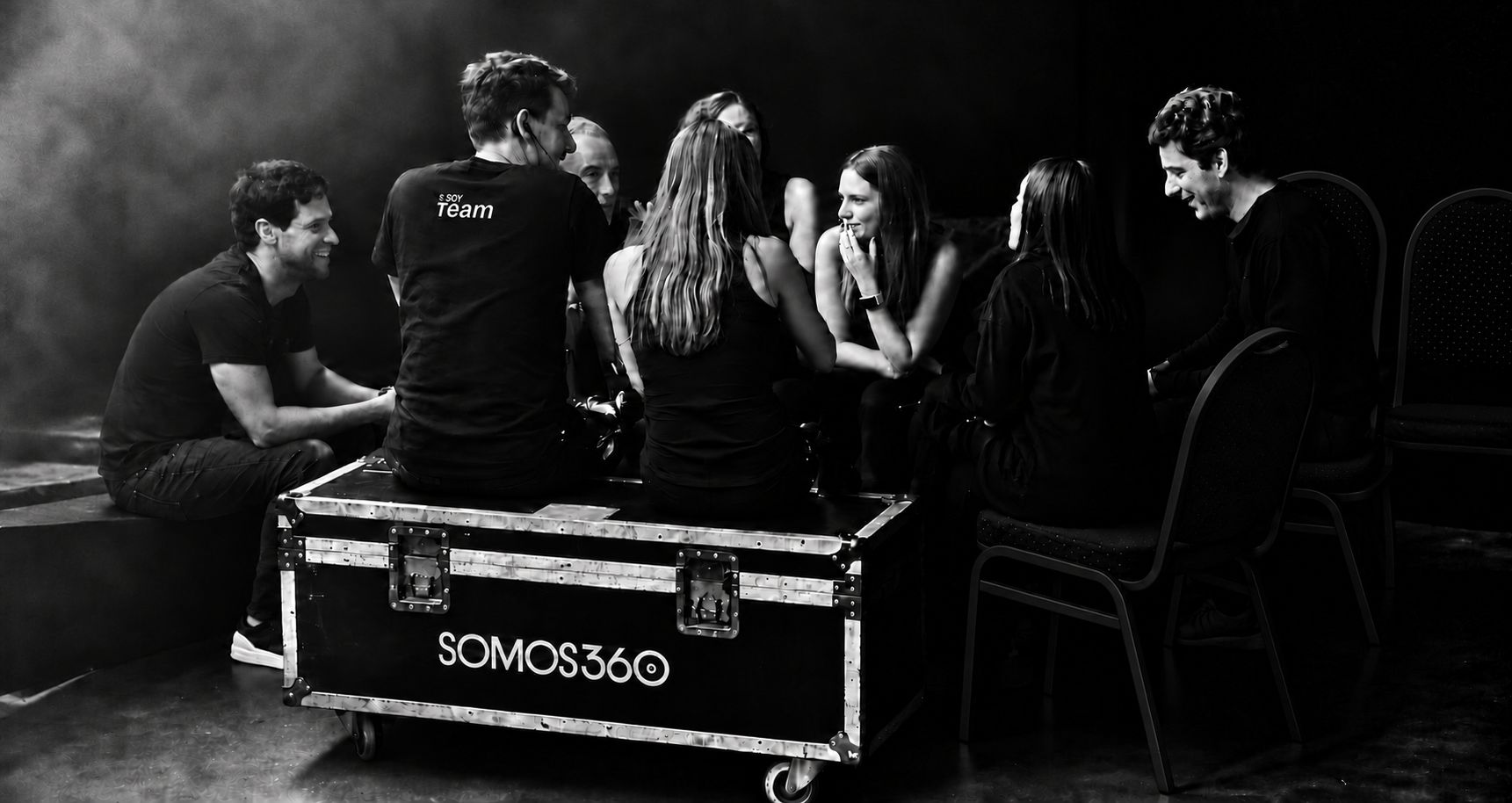 El equipo de SOMOS 360 reunido alrededor de un case con el logo SOMOS360, en blanco y negro
